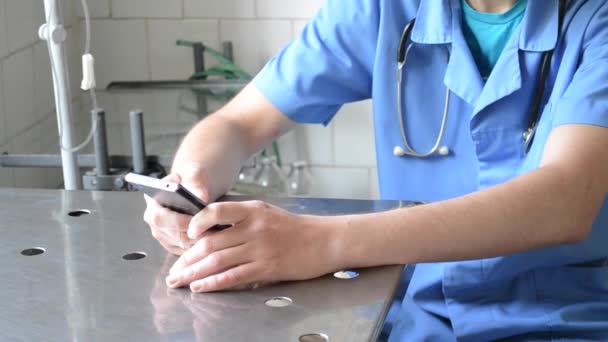 Doctor sentado en la mesa y usando el teléfono — Vídeos de Stock