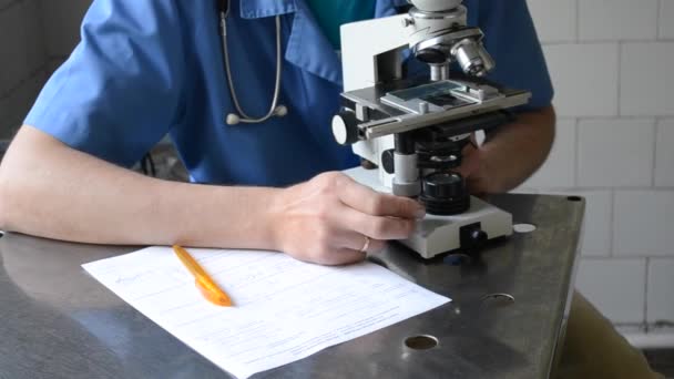 Medico e microscopio, carta bianca e penna gialla — Video Stock