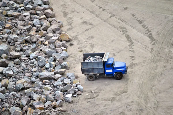 Carro de carga com pedras perto de pedra enorme em pedreira de granito — Fotografia de Stock