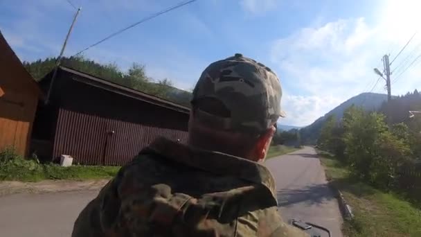 Man rijdt zwarte quad fiets of ATV op de weg in het bergdorp in de zomer — Stockvideo