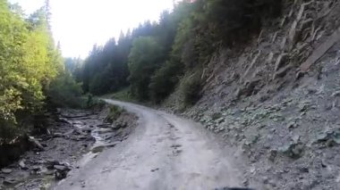Yaz güneşli bir günde dağlık toprak yolda araba kullanmak. POV