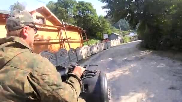 L'uomo cavalca quad nero o ATV su strada sterrata nel villaggio di montagna — Video Stock