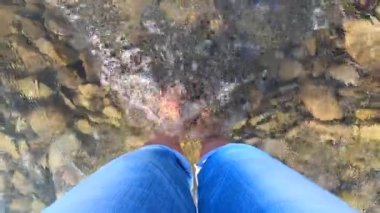 Kız dağlardaki kayalık bir nehrin dibinde duruyor.