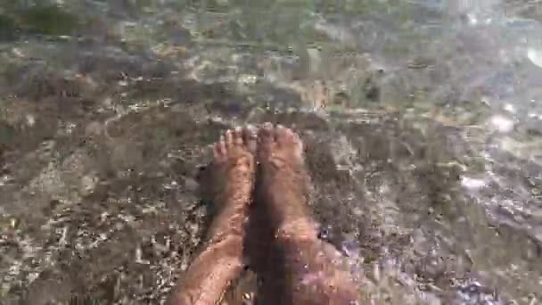 2人の女性の足は砂のビーチで清潔で透明な水にあります — ストック動画