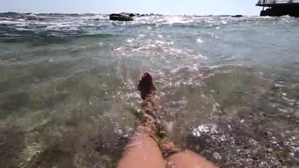 Dois pés femininos estão em água limpa e transparente na praia de areia — Vídeo de Stock