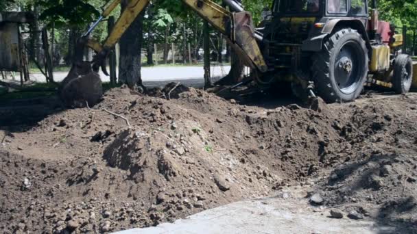 Tractor slaat de grond in. Backhoe stapelt de grond op close-up. — Stockvideo