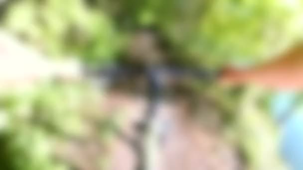 Blurred background. A woman on bicycle rides along narrow path on river bank — Stock Video