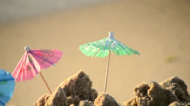 Kumsaldaki bir kokteyl standı için kağıttan yapılmış küçük plaj şemsiyeleri.