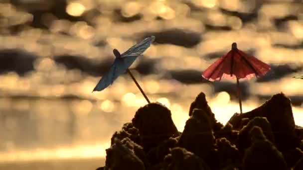 Pequenos guarda-sóis de praia feitos de papel para um coquetel na praia de areia — Vídeo de Stock