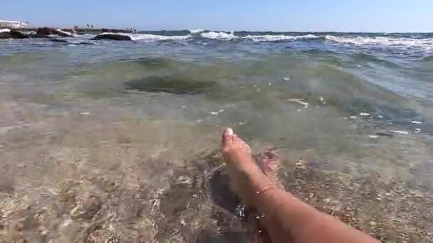 İki kadın ayakları deniz kıyısındaki kumlu sahilde şeffaf sularda. — Stok video