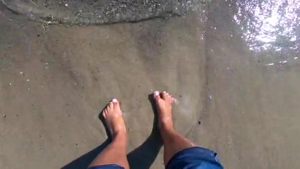 女の子は砂浜に裸の足を立って、砂の中に指を埋める — ストック動画