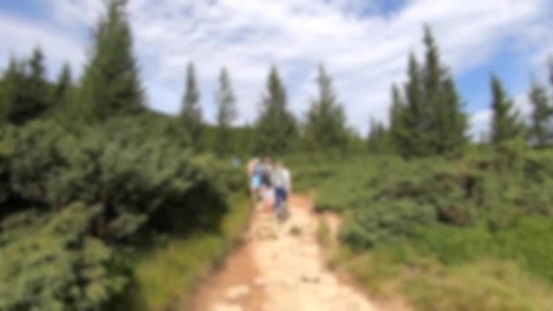 Blurred background. People walk on dirt mountain trail while hiking in mountains — Stock Video