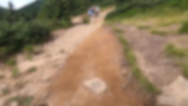 Blurred background. People walk on dirt mountain trail while hiking in mountains — Stock Video