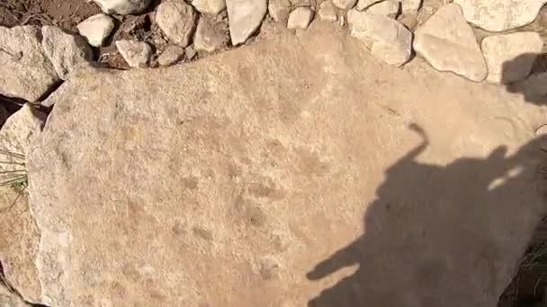 Человек взбирается на гору по грунтовой дороге с камнями летний день — стоковое видео