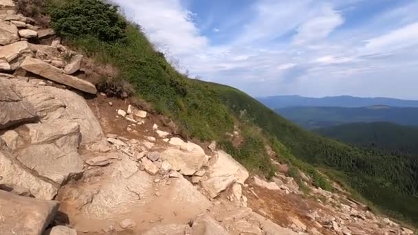 El hombre sube a la montaña en un camino de tierra con piedras día de verano — Vídeos de Stock