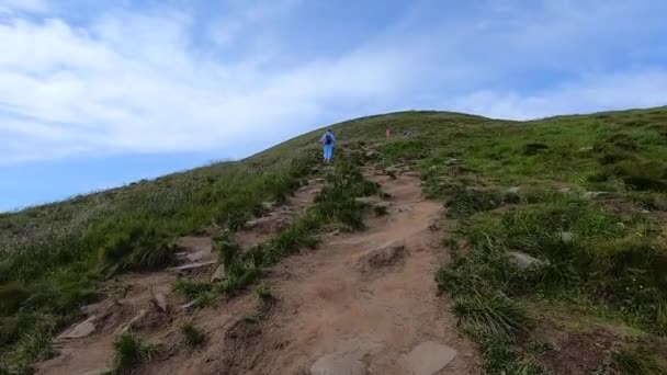 男は夏の日に石で未舗装の道路で山に登る — ストック動画