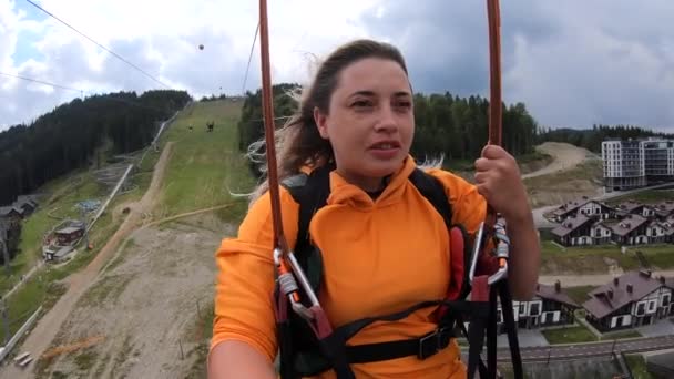 Tourist girl is riding or sliding zipline or trolley over nature from mountain — Stock Video
