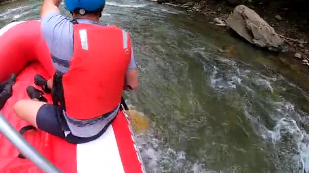 Rafting. Erkekler kırmızı şişme kayıkta oturur, kürek çeker ve dağ nehrinde yüzer. — Stok video