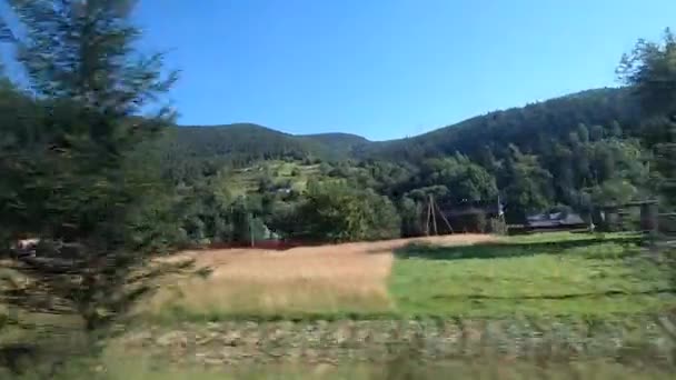 Vue depuis la fenêtre du bus. La voiture roule sur la route dans la forêt et les montagnes de la ville — Video