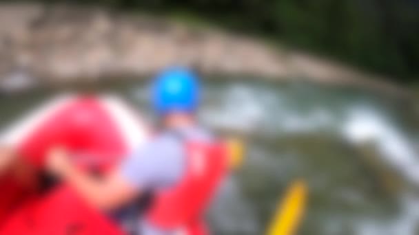 Rafting arrière-plan flou. Les hommes s'assoient dans le bateau gonflable rouge, pagaie — Video