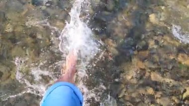 Çıplak ayaklı kız sığ nehir taşlarının üzerine sıkar güneşli yaz günü.