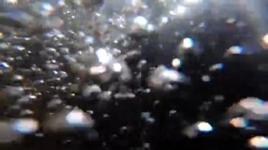 Su altında dönen ve yüzen beyaz ve şeffaf hava kabarcıkları