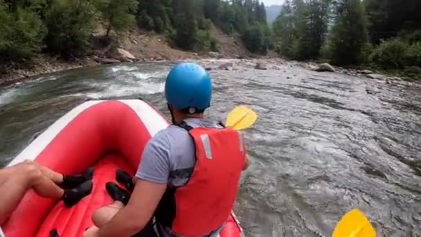 La gente se sienta en un bote de goma inflable y flota por el río de la montaña — Vídeos de Stock