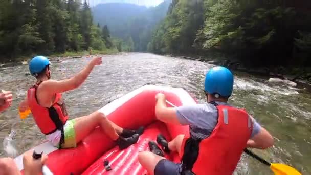 La gente se sienta en un bote de goma inflable y flota por el río de la montaña — Vídeo de stock