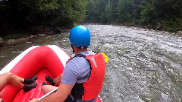 La gente se sienta en un bote de goma inflable y flota por el río de la montaña — Vídeo de stock
