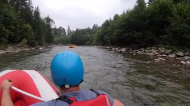 İnsanlar şişme bir teknede oturur ve dağ nehrinde yüzerler.