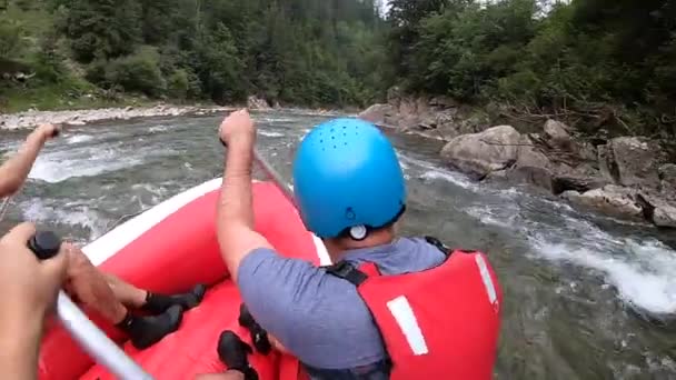 Люди сідають у надувний каучуковий човен і пливуть вниз гірською річкою. — стокове відео