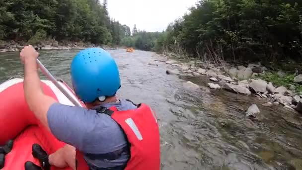 Mensen zitten in een opblaasbare rubberboot en drijven de bergrivier af. — Stockvideo