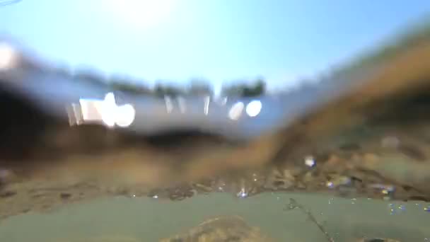 El agua que fluye de un río poco profundo en un día soleado primer plano. Cielo despejado sin nubes — Vídeos de Stock