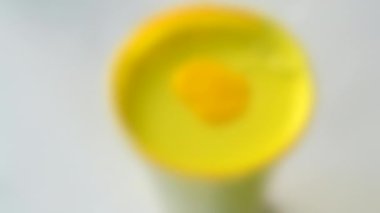Arka plan bulanık. Plastik bir şişede sarı boya karıştırmak