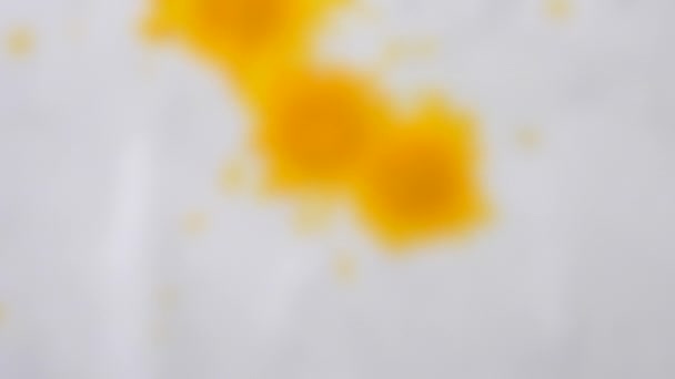 Blurred background. Yellow, sunny ink, paint droplets spreads on the paper — Stock Video