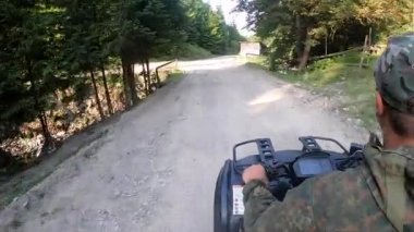 Güneşli yaz gününde dağın tepesinde toprak yolda bisiklete binen bir adam.