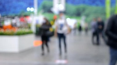 Arka plan bulanık. İnsanlar büyük uzay binasının içinde yürürler.