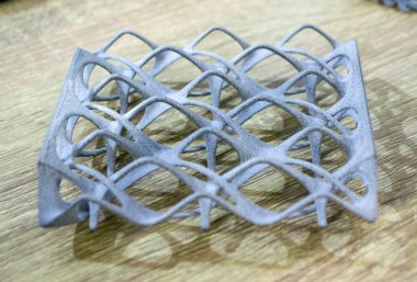 Podyum tozunun 3D yazıcısında yakın plan çekilmiş bir nesne. Termoplastik gri renkten üç boyutlu model. Hızlı prototip, baskı ürünleri. İlerici modern katkı teknolojisi
