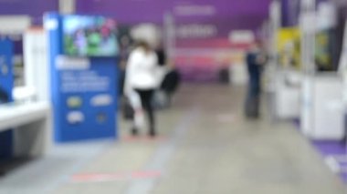 Arka plan bulanık. İnsanlar büyük uzay binasının içinde yürürler.