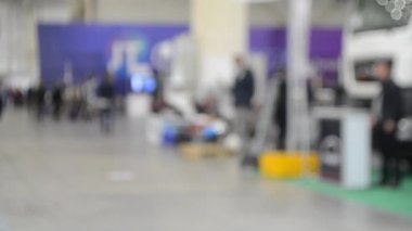 Arka plan bulanık. İnsanlar büyük uzay binasının içinde yürürler.