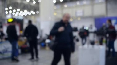 Arka plan bulanık. İnsanlar büyük uzay binasının içinde yürürler.