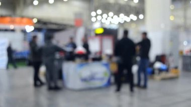 Arka plan bulanık. İnsanlar büyük uzay binasının içinde yürürler.