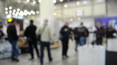 Arka plan bulanık. İnsanlar büyük uzay binasının içinde yürürler.