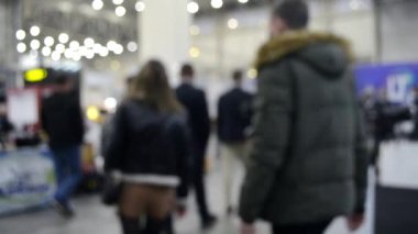 Arka plan bulanık. İnsanlar büyük uzay binasının içinde yürürler.