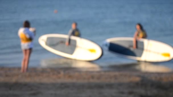 Rozmazané pozadí. Mnoho lidí stojí na moři a fotí se sup board — Stock video