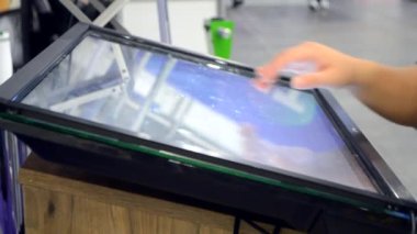 Kız dokunmatik ekranla parmaklarını büyük ekranda gezdiriyor..