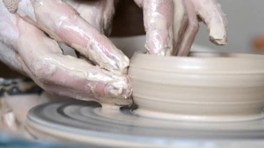 Elleri duvar sürahisine dublaj yapan bir adam. Çemberdeki makrodan kilden yontuyor.