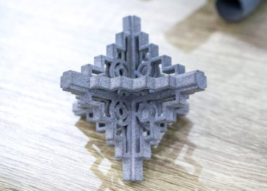 Podyum tozunun 3D yazıcısında yakın plan çekilmiş bir nesne. Termoplastik gri renkten üç boyutlu model. Hızlı prototip, baskı ürünleri. İlerici modern katkı teknolojisi