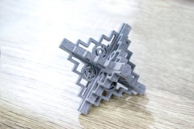 Podyum tozunun 3D yazıcısında yakın plan çekilmiş bir nesne. Termoplastik gri renkten üç boyutlu model. Hızlı prototip, baskı ürünleri. İlerici modern katkı teknolojisi