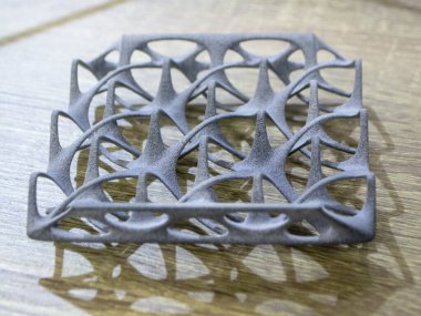 Podyum tozunun 3D yazıcısında yakın plan çekilmiş bir nesne. Termoplastik gri renkten üç boyutlu model. Hızlı prototip, baskı ürünleri. İlerici modern katkı teknolojisi